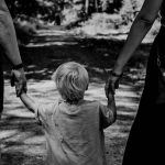 grayscale photo of woman in black dress holding child in black shirt