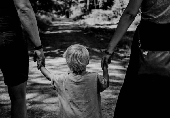 grayscale photo of woman in black dress holding child in black shirt